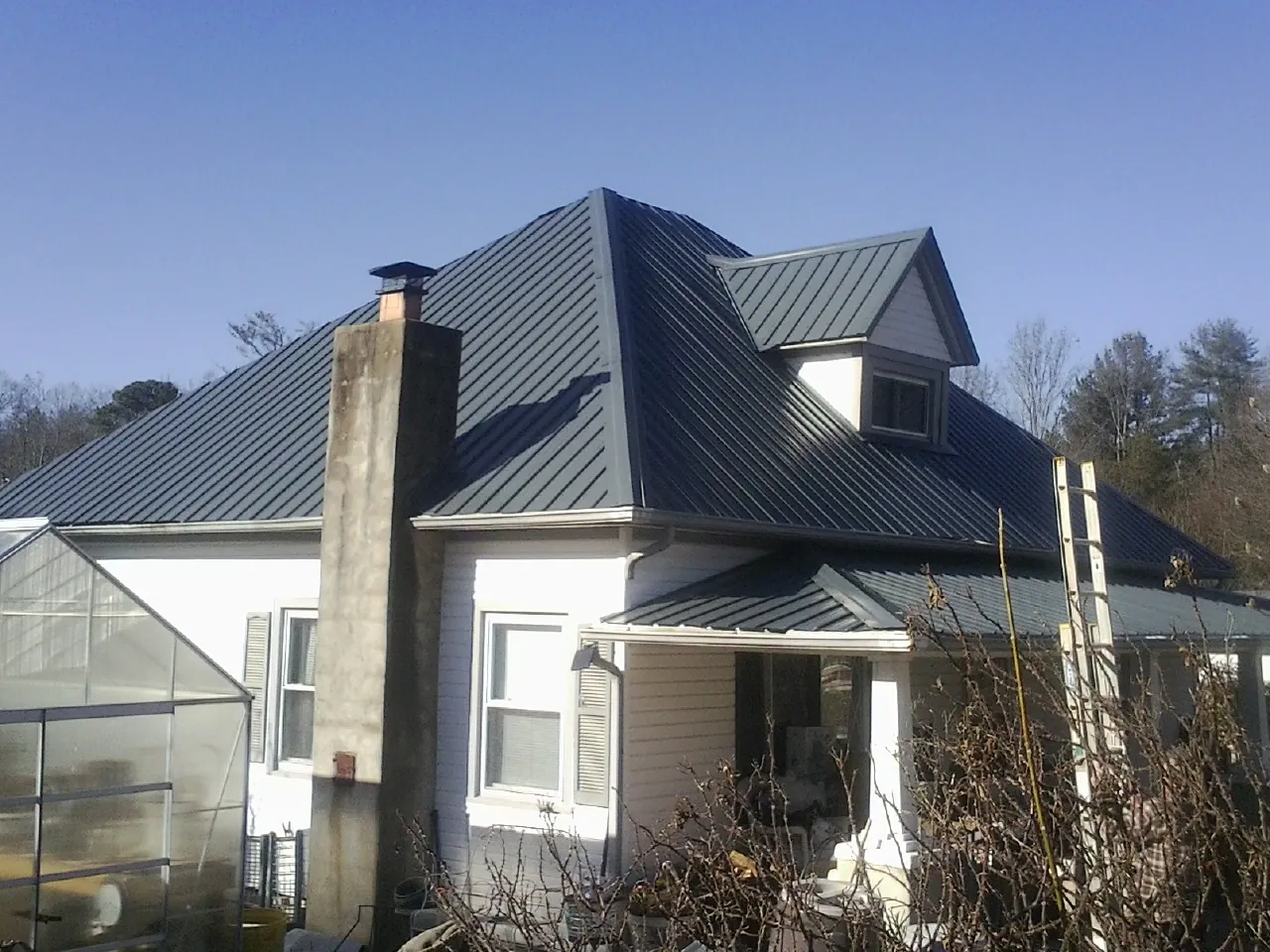 Dark blue standing seam metal roof on a white farmhouse with dormer — Slate & Tile Roof Repair by Roofing Brothers in Pine Brook