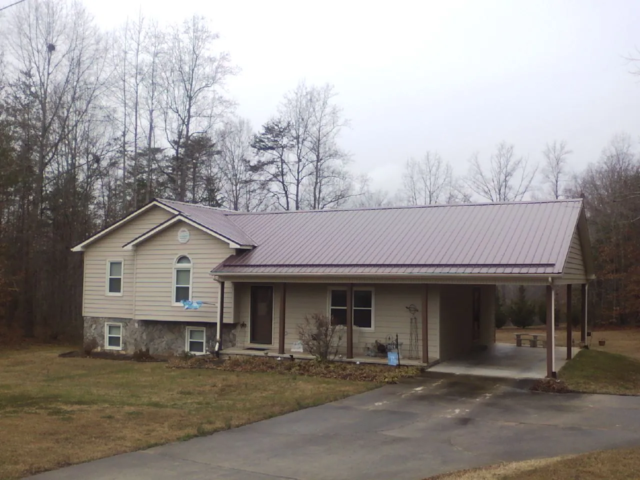 Burgundy metal roof on a tan split level home with an attached carport in Pine Brook