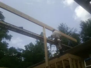 Carpenter setting a ridge beam over a new addition frame — Ice Dam Removal by Roofing Brothers in Pine Brook