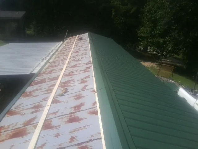 Old rusted panels beside newly installed green metal roofing — Wind Damage Roof Repair by Roofing Brothers in Pine Brook
