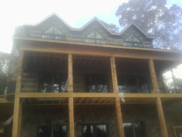 Dormers and porch framing on a large log home under construction — Roof Coating work by our crew in Pine Brook