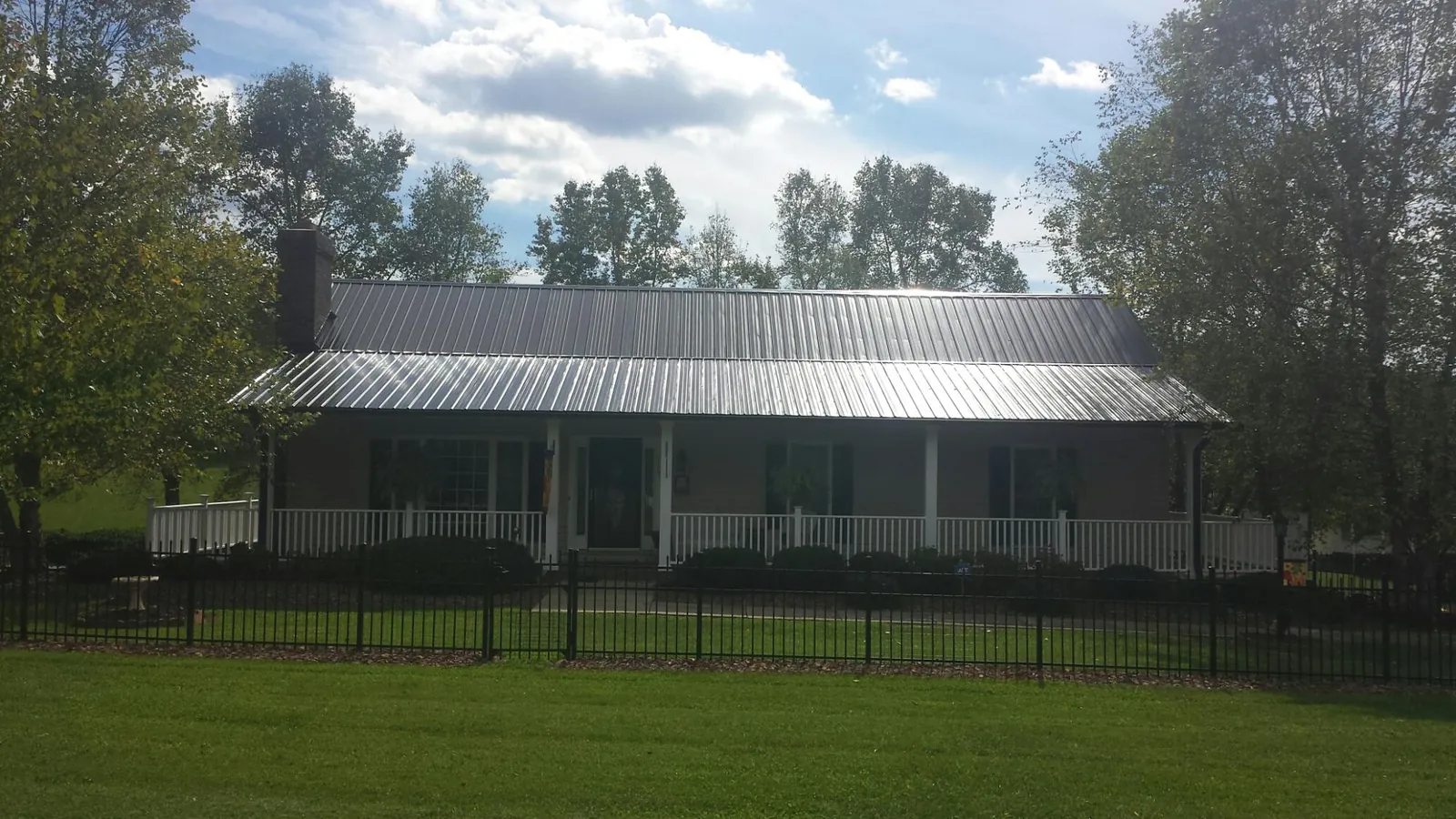 Gray metal roof on a brick ranch with a full width front porch — Gutter Guard Installation work by our crew in Pine Brook