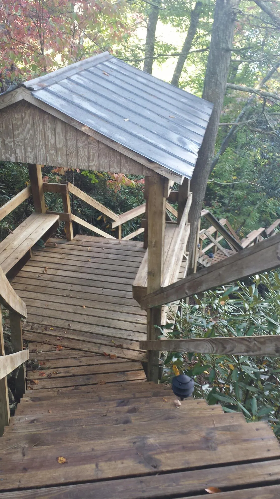 Metal roofed shelter over wooden steps on a wooded walkway — Skylight Repair & Installation work by our crew in Pine Brook